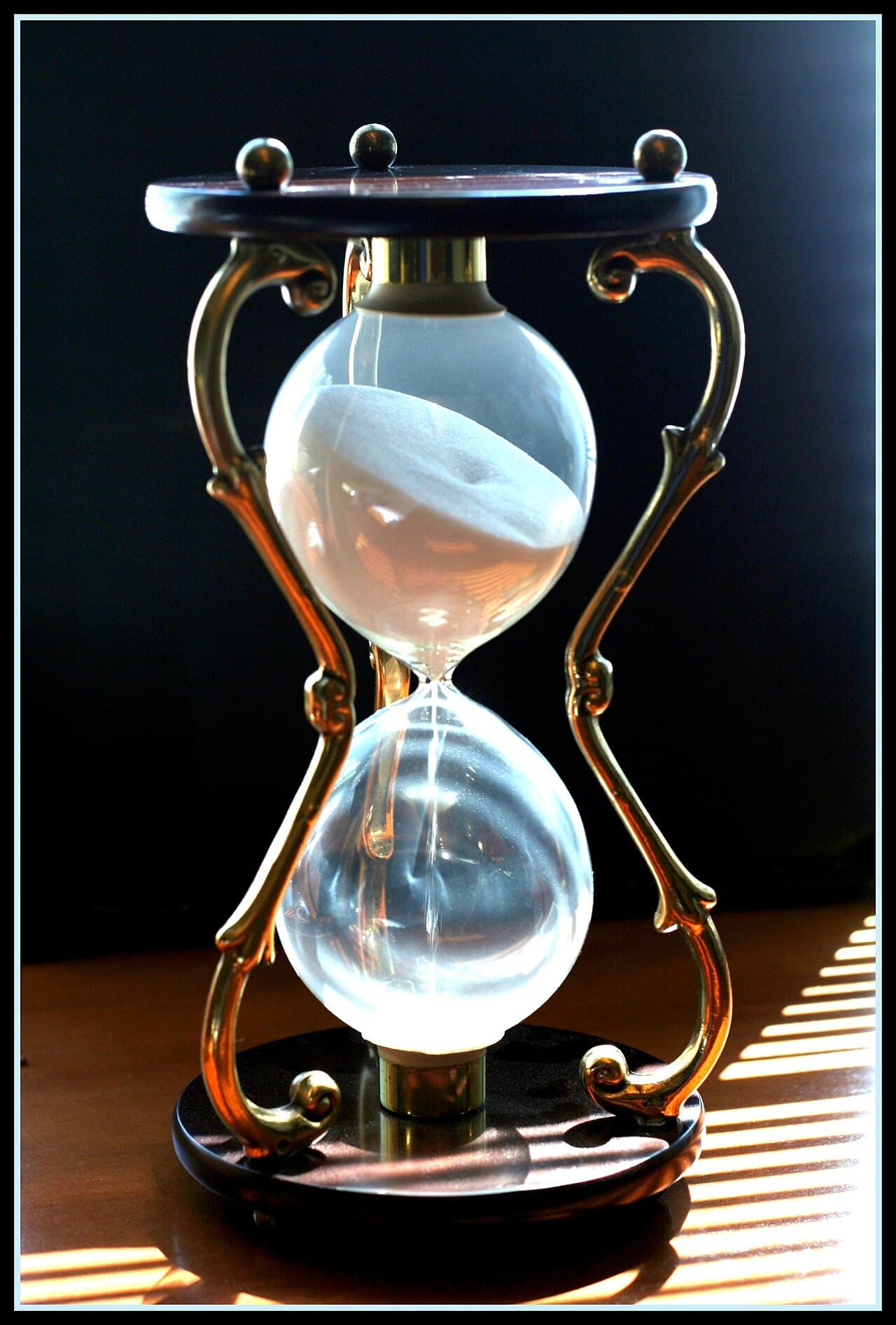 An hourglass with running sand, illustrating the epoch-length waiting period when unstaking SOL
